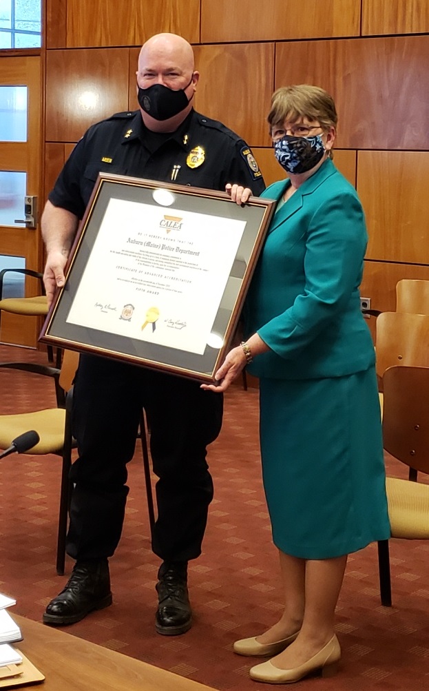 A woman and a man hold a framed certificate